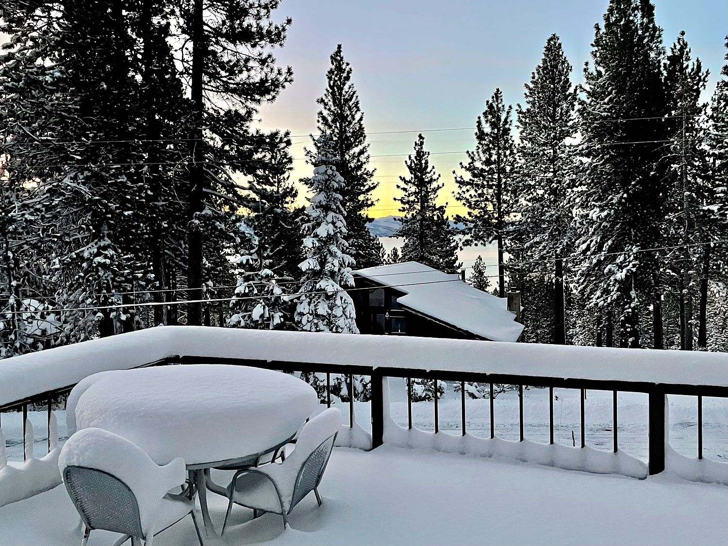 Snow-covered deck table at Kinpine House with Lake Tahoe visible at dawn
